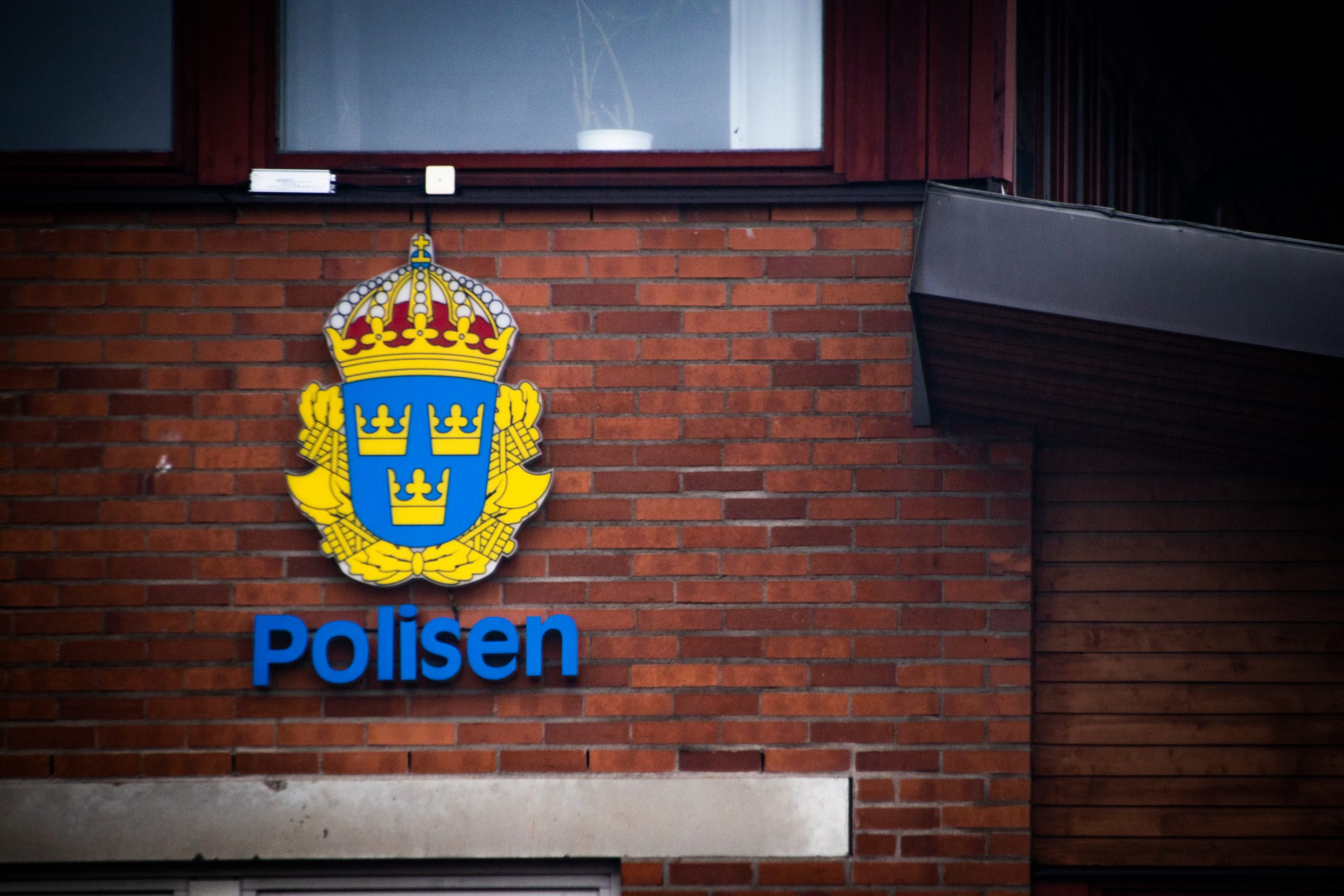 Polisens heraldiska vapen i dagsljus mot en tegelvägg.