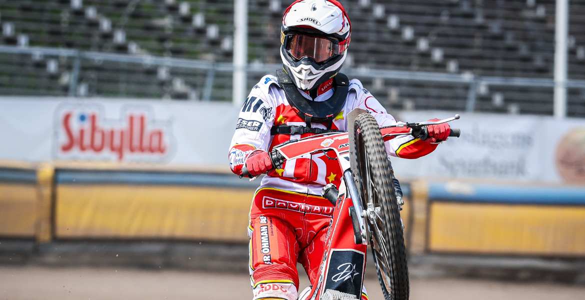 Speedwayförare som kör på bakhjulen på banan.