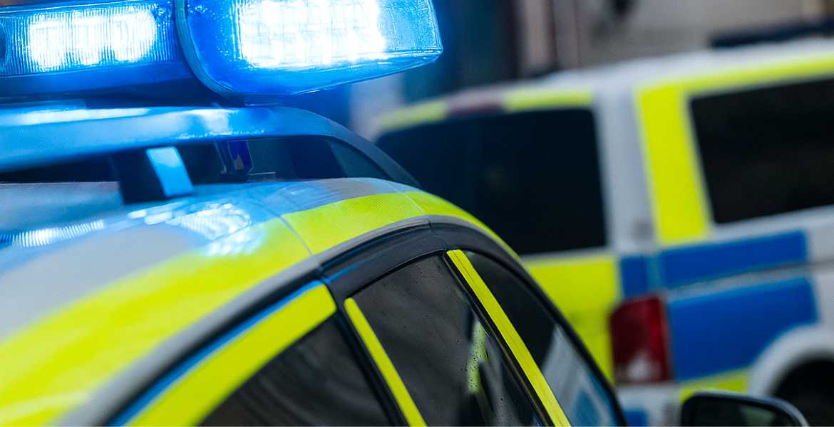 Polisbilar med blåljussirener i kvällsmörker.